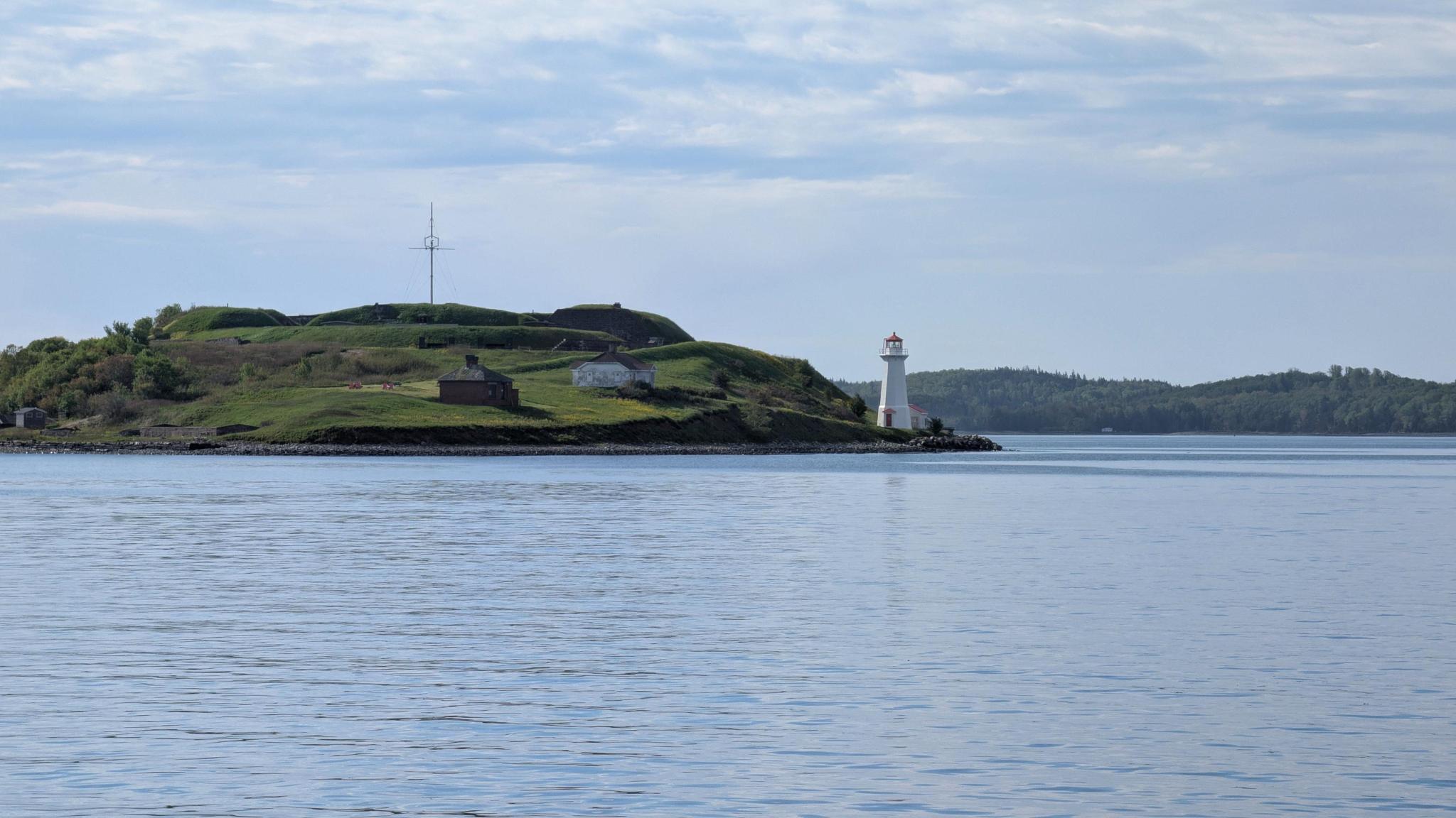 Source image 2 showing Georges Island lighthouse, grassy hill, and calm blue water.